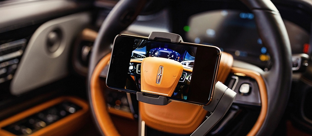 Se muestra un teléfono móvil en uso para entregar un control remoto privado que muestra un vehículo Lincoln Black Label.