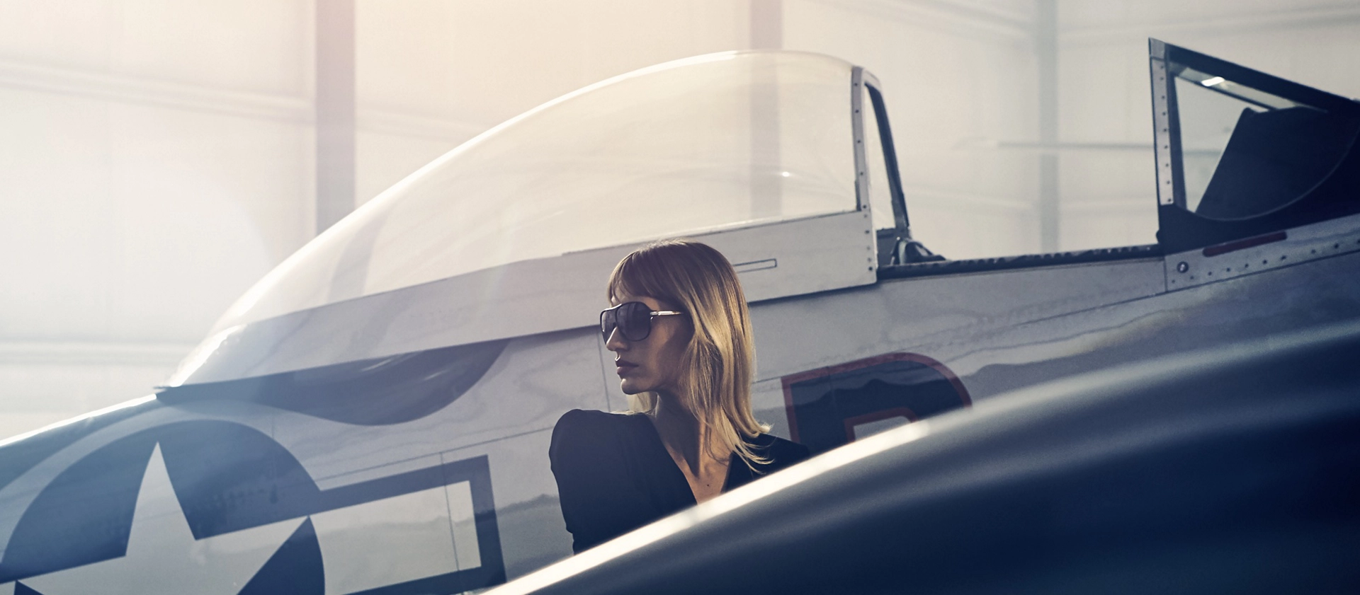  A woman is shown next to a vintage airplane to evoke the inspiration for the 2025 Lincoln Black Label Flight theme