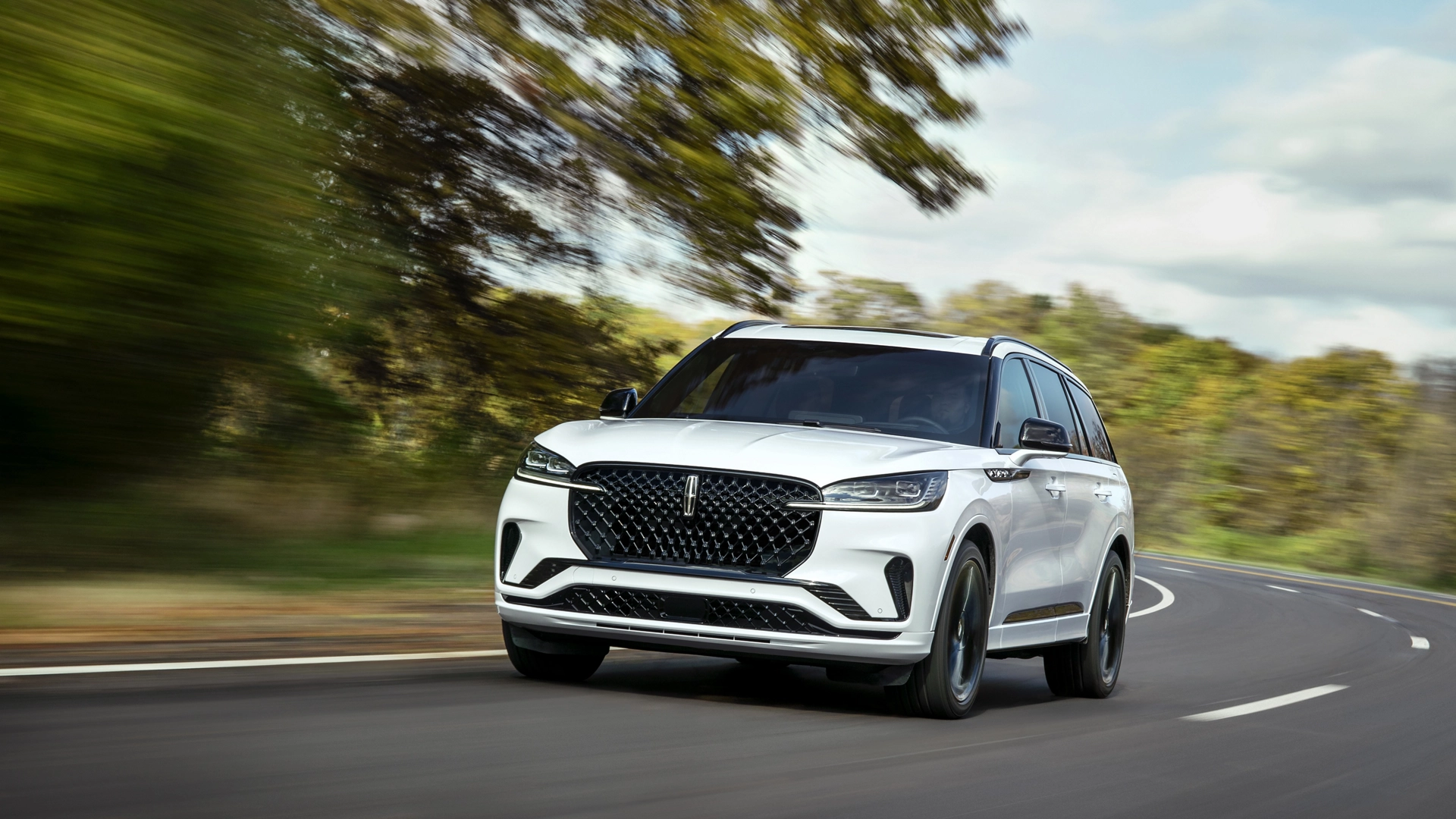 A 2025 Lincoln Aviator® SUV is being driven on a country road