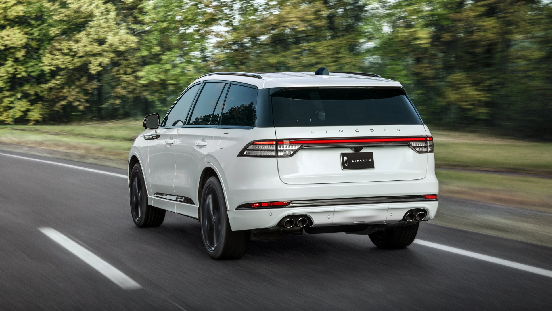 The rear of the 2025 Lincoln Aviator driving down a road.