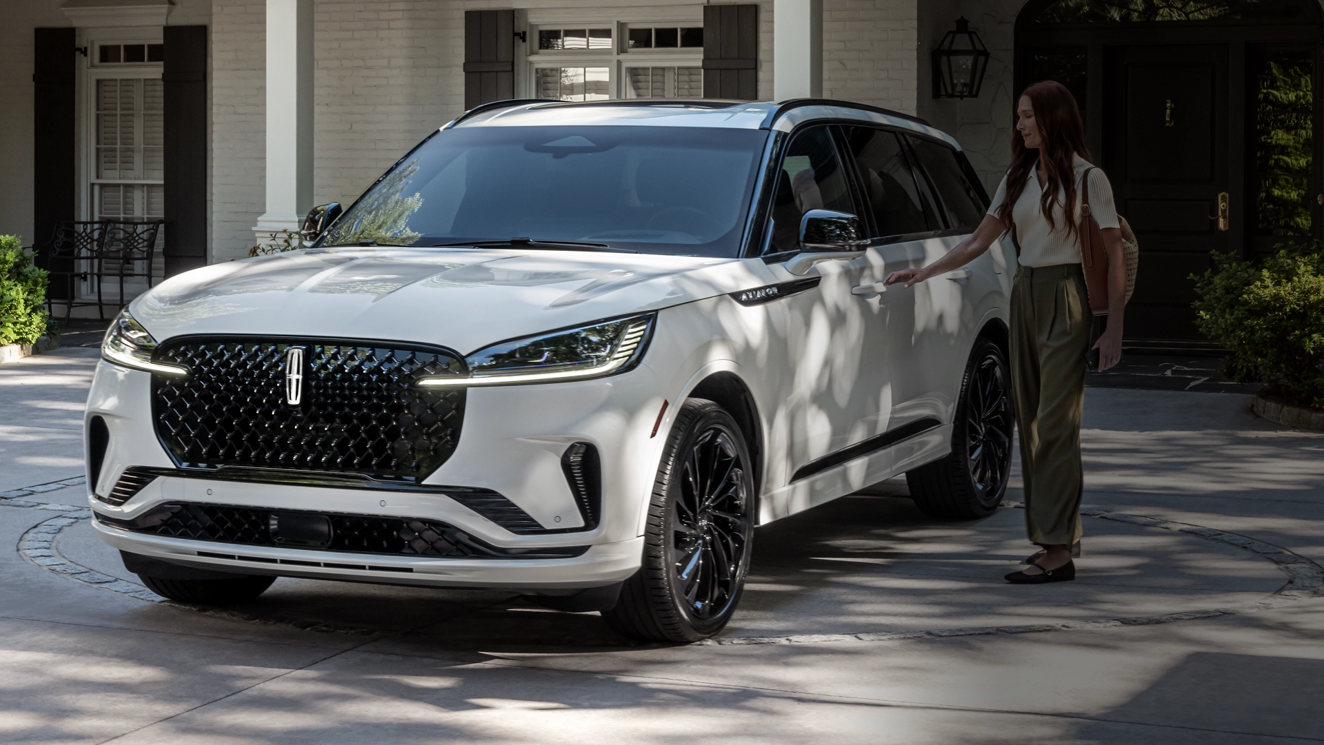 A person approaches a 2025 Lincoln Aviator® while holding a mobile phone.