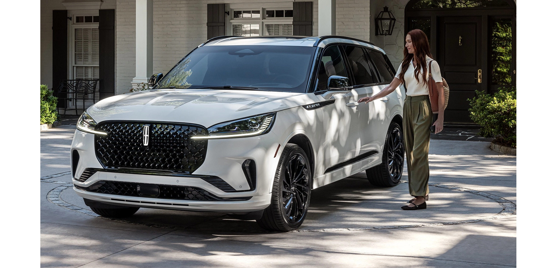 A person approaches a 2025 Lincoln Aviator® while holding a mobile phone.