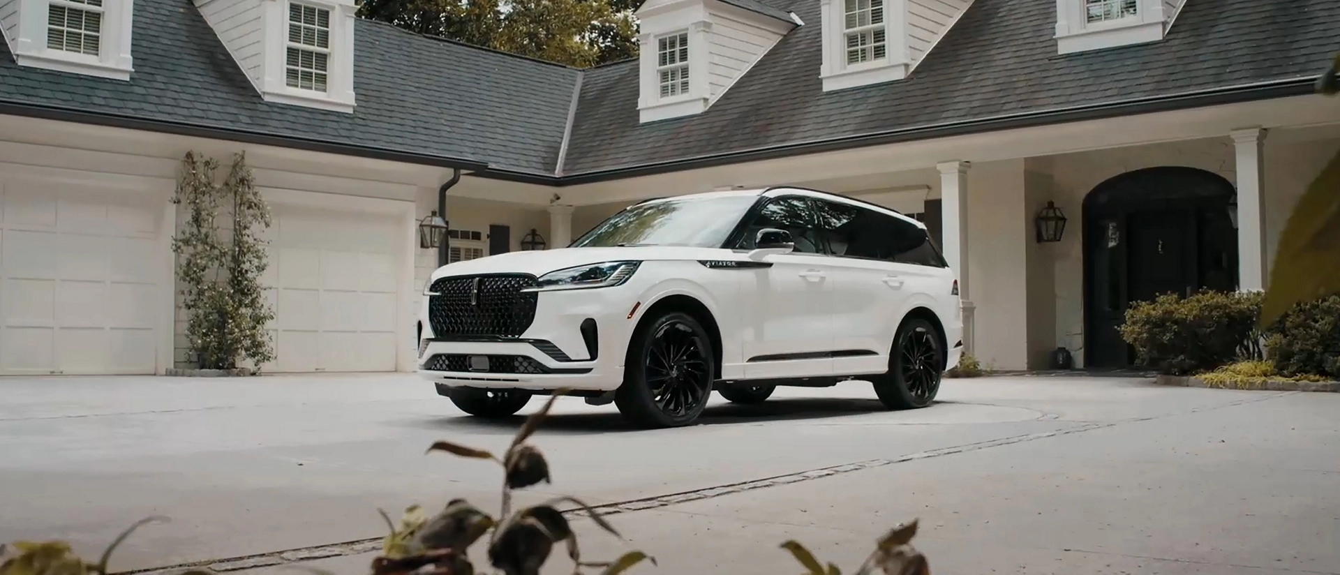 A 2025 Lincoln Aviator® SUV is parked in the driveway of a luxury home