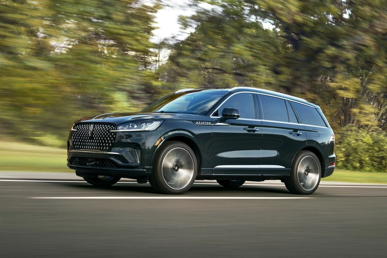 A 2026 Lincoln Aviator® SUV is shown driving on a forested road