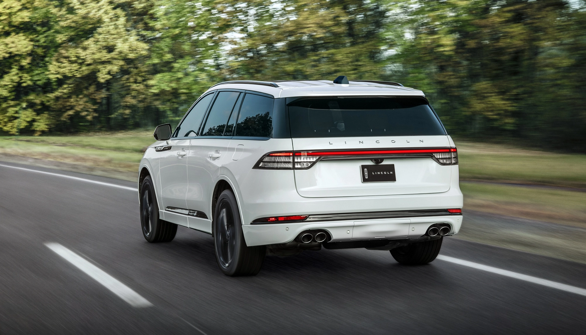 A 2026 Lincoln Aviator® SUV is shown driving on a forested road