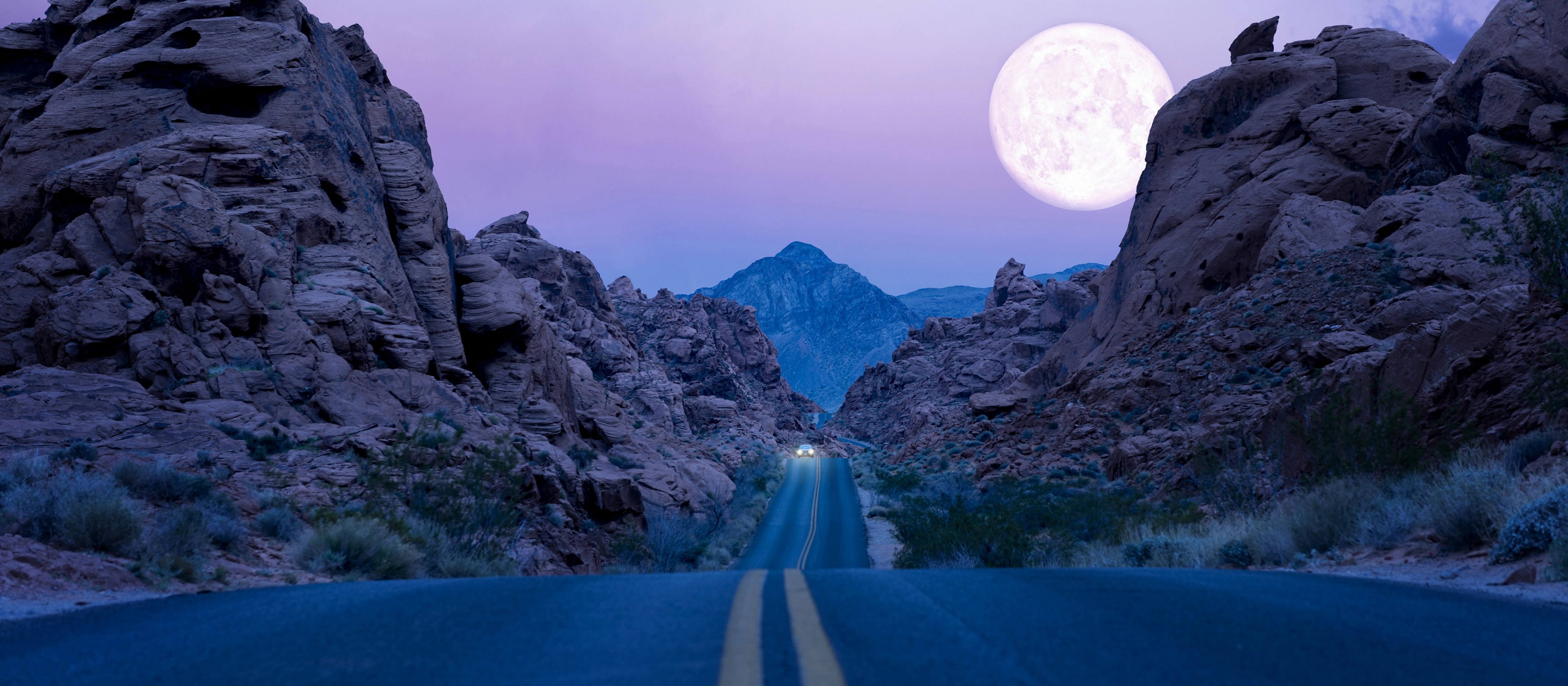 The moon rises above a desert southwest highway at night