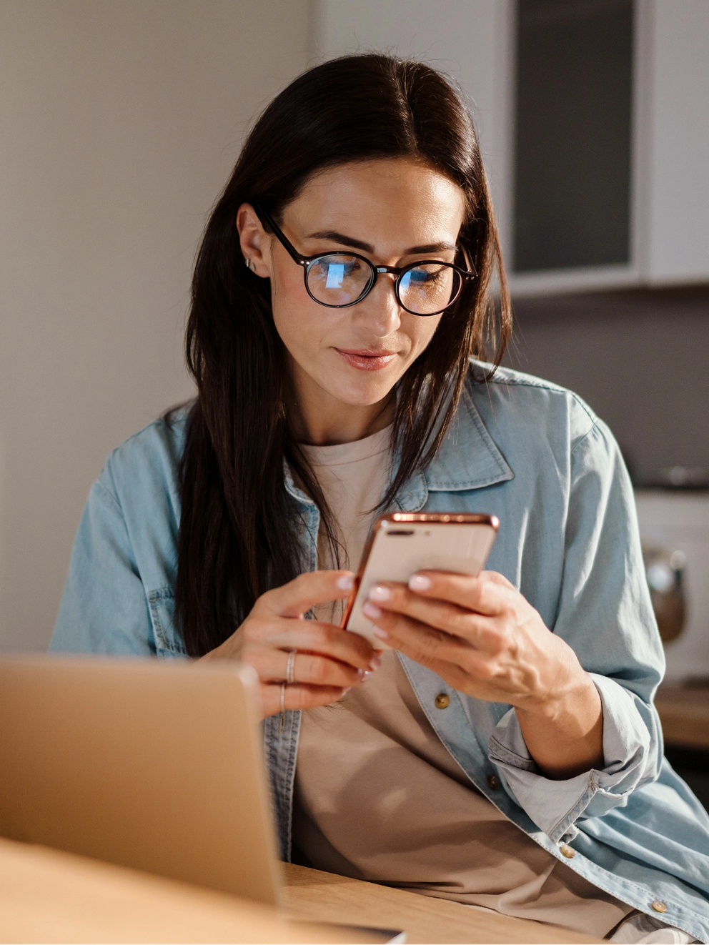 A woman sitting at a desk and looking at a cell phone.